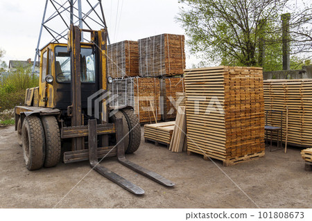 Large lift truck and stacks of new wooden boards and studs at the lumber yard. Wooden plates on piles for furniture materials 101808673
