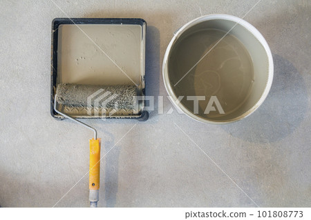High angle of paint roller in tray with paint can on concrete floor. 101808773