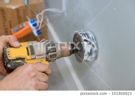 Installing electrical wires in wall by drilling holes in drywall Installing electrical wires in wall by drilling holes in drywall 101808923
