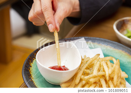 Woman's hand eating potato fries 101809051