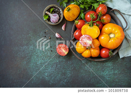 Various colorful tomatoes and parsley leaves on a dark stone background. Organic food. View from above. Copy space. Various colorful tomatoes and parsley leaves on a dark stone background. Organic food. View from above. Copy space. 101809738