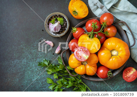 Various colorful tomatoes and parsley leaves on a dark stone background. Organic food. View from above. Copy space. Various colorful tomatoes and parsley leaves on a dark stone background. Organic food. View from above. Copy space. 101809739