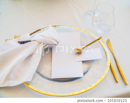 Wedding Table place with invitation card and porcelain plates decorated with olive branches top view. Elegant modern template with square blank paper card flat lay. Mediterranean mockup copy space 101810123