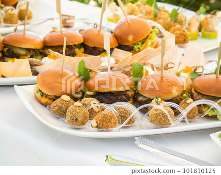 Banquet table with snacks food on plates hamburger party dinner table - buffet table after wedding ceremony 101810125