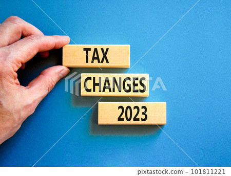 Tax changes 2023 symbol. Concept words Tax changes 2023 on wooden blocks on a beautiful blue table blue background. Businessman hand. Business Tax changes 2023 concept. Copy space. 101811221