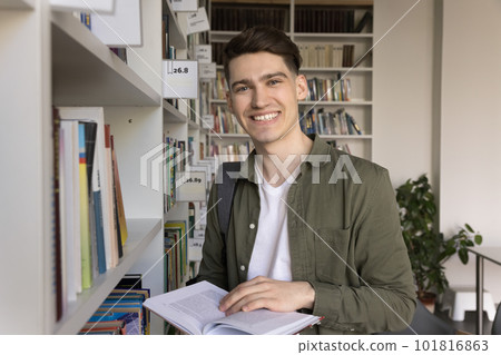 Student guy look at camera posing in library with textbook Student guy look at camera posing in library with textbook 101816863