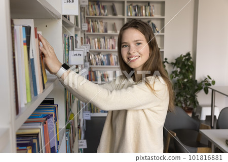 Portrait of pretty teenage student girl choose textbook in library 101816881
