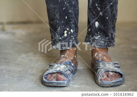 Feet of a construction worker in old dirty clothes and shoes Feet of a construction worker in old dirty clothes and shoes 101816962