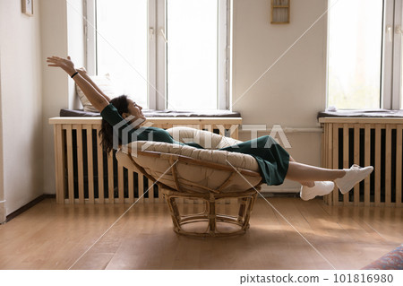 Happy young woman relaxing seated in modern chair Happy young woman relaxing seated in modern chair 101816980