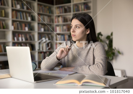 Pensive schoolgirl thinks about correct answer do homework in library 101817040