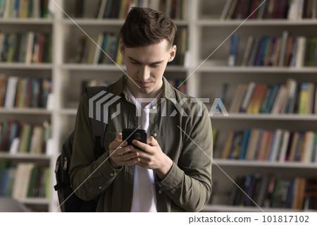 Student checks mobile phone message standing in university library 101817102