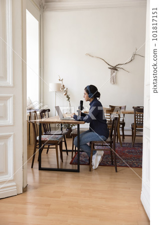 Female in headphones looks at laptop screen, speaking into microphone 101817151