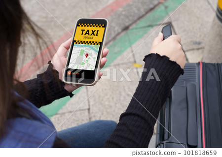 Woman with baggage in downtown city street ordering taxi using smart phone app Booking taxi using application online on smart phone. 101818659