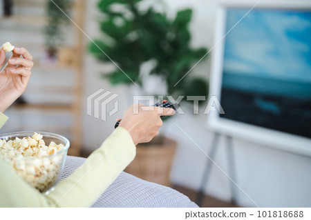 Asian woman Watching smart TV and using remote controller Hand holding television audio remote control at home with the remote control television Asian woman Watching smart TV and using remote controller Hand holding television audio remote control at home with the remote control television 101818688