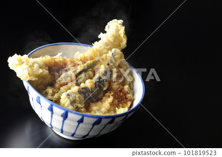 A hot tempura bowl with conger eel, eggplant, pumpkin and green bean tempura on a black background A hot tempura bowl with conger eel, eggplant, pumpkin and green bean tempura on a black background 101819523