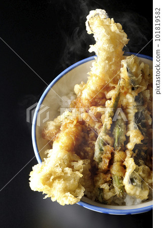 A bird's-eye view of a hot tempura bowl topped with conger eel, eggplant, pumpkin, and green bean tempura on a black background A bird's-eye view of a hot tempura bowl topped with conger eel, eggplant, pumpkin, and green bean tempura on a black background 101819582