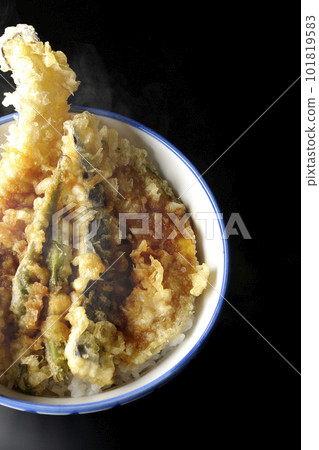 A bird's-eye view of a hot tempura bowl topped with conger eel, eggplant, pumpkin, and green bean tempura on a black background 101819583