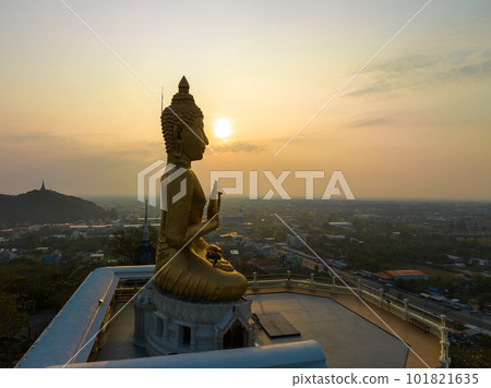 aerial view The sun was on the hand of the golden Buddha in Phetchaburi. aerial view scenery golden sky in the morning at the golden Buddha on the high mountain. bright yellow sky background.  101821635