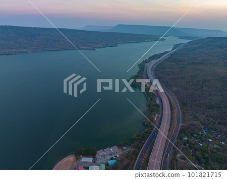 aerial view orange lights on the expressway along the route along the Lam Ta Khong Dam. beautiful scenery in the early morning wind mill on the mountains, rivers and sweet skies background. aerial view orange lights on the expressway along the route along the Lam Ta Khong Dam. beautiful scenery in the early morning wind mill on the mountains, rivers and sweet skies background. 101821715