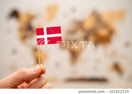 Denmark flag in mans hand on the wooden world map background. Global economy and geopolitics concept.  101822514