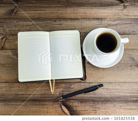 Coffee in a cup, notepad and pen on a wooden table. 101825538
