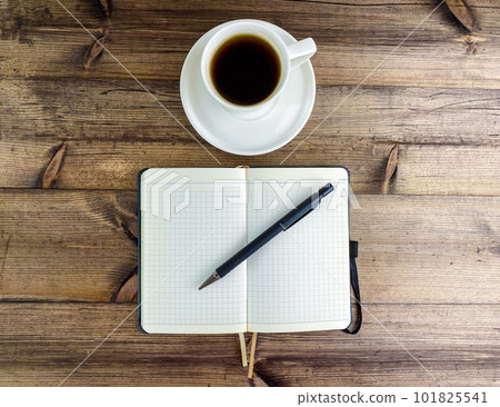 Coffee in a cup and a notepad with a pen, top view. 101825541