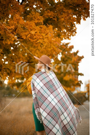 autumn woman in a green dress, brown hat, plaid, against the background of an autumn tree autumn woman in a green dress, brown hat, plaid, against the background of an autumn tree 101827470
