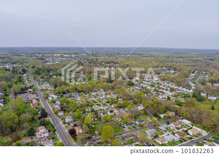 An aerial view of small American town residential complex district with houses and roads surrounded by spring trees can be seen from above. 101832263