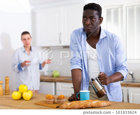 Man pouring coffee into cup in morning, having quarrel with his wife 101833624