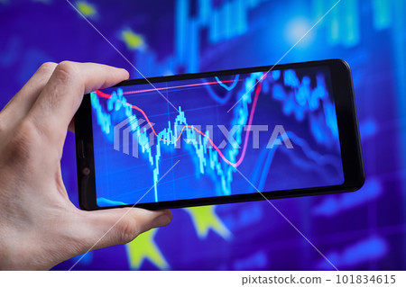 Trader analyzes stock market data in smartphone on the background of stock charts Trader analyzes stock market data in smartphone on the background of stock charts 101834615