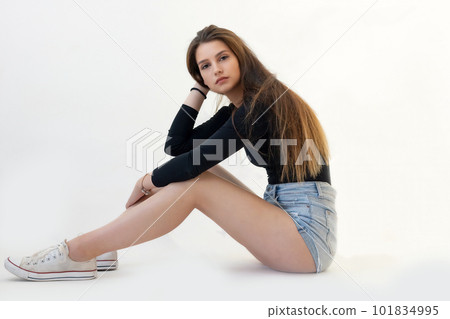 Young long legged girl is sitting on floor . Young long legged girl is sitting on floor . 101834995