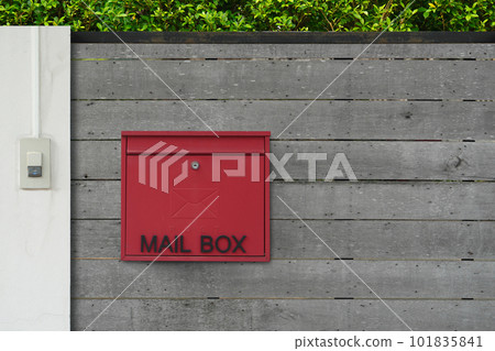 red and black mailbox hangs on the wooden fence door in front of the house, wall green tree background, object, decor, modern, copy space red and black mailbox hangs on the wooden fence door in front of the house, wall green tree background, object, decor, modern, copy space 101835841