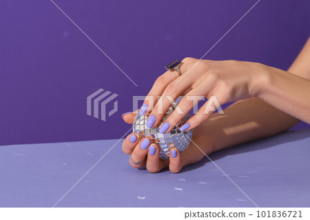 Manicured womans hands holding disco ball on violet background. Manicure, pedicure beauty salon concept Manicured womans hands holding disco ball on violet background. Manicure, pedicure beauty salon concept 101836721