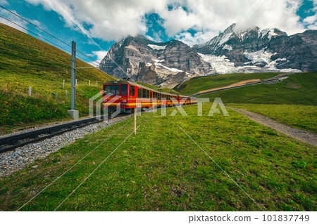 Electric tourist cogwheel train on the green slope in Switzerland Electric tourist cogwheel train on the green slope in Switzerland 101837749