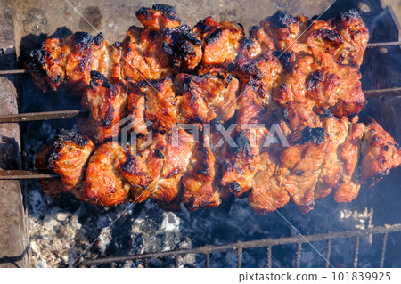 Roasted meat cooked at barbecue, closeup. Spicy marinated meat cook on bbq grill. Pork meat, shashlik, prepared on grill outdoor. Shish kebab cooking outdoors Roasted meat cooked at barbecue, closeup. Spicy marinated meat cook on bbq grill. Pork meat, shashlik, prepared on grill outdoor. Shish kebab cooking outdoors 101839925