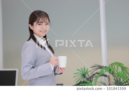 拿著咖啡杯走在辦公室裡的女商人 1 101841509