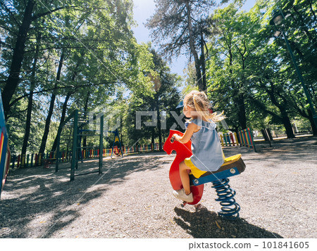 Little girl swinging on a swing-spring in the playground 101841605