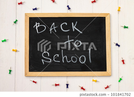Back to school black chalk board on a white wooden background, color pins. Top view. Copyspace. Education concept. 101841702