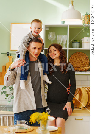 a happy family. pregnant mom, son and dad In the kitchen. a cozy house a happy family. pregnant mom, son and dad In the kitchen. a cozy house 101842172