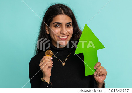 Indian woman winner holding arrow sign pointing up showing golden bitcoins cryptocurrency mining BTC 101842917
