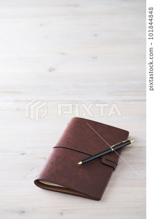 A notebook with a leather cover and a black pen 101844848