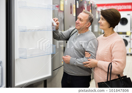 European spouses choose a refrigerator, examining it European spouses choose a refrigerator, examining it 101847806