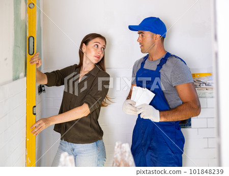 Woman using spirit level on wall with repairman Woman using spirit level on wall with repairman 101848239