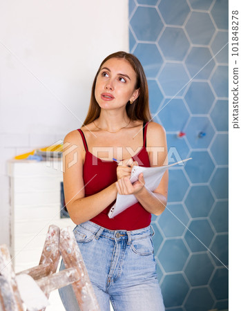 Woman with documents in her hands checks the quality of the completed repairs in cottage room 101848278