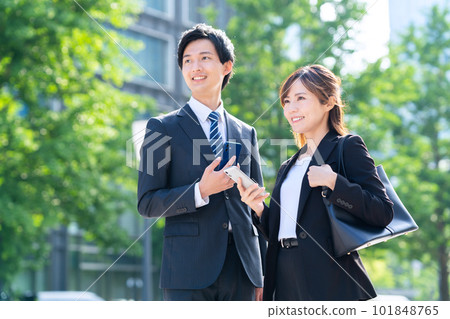 Male and female businessmen using smartphones in office district Male and female businessmen using smartphones in office district 101848765