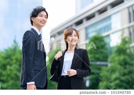 Male and female businessmen walking side by side in an office district Male and female businessmen walking side by side in an office district 101848780
