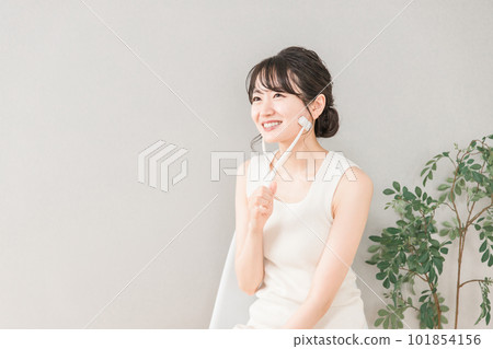Asian woman massaging with facial roller Asian woman massaging with facial roller 101854156