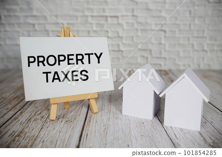 Property Taxes text message with calculator and house model on wooden background 101854285