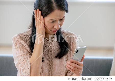 一位因看智能手機而煩惱的高級女性 101854686