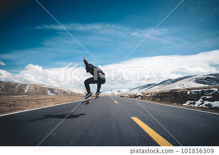 Asian woman skateboarder skateboarding on snowy  country road 101856309